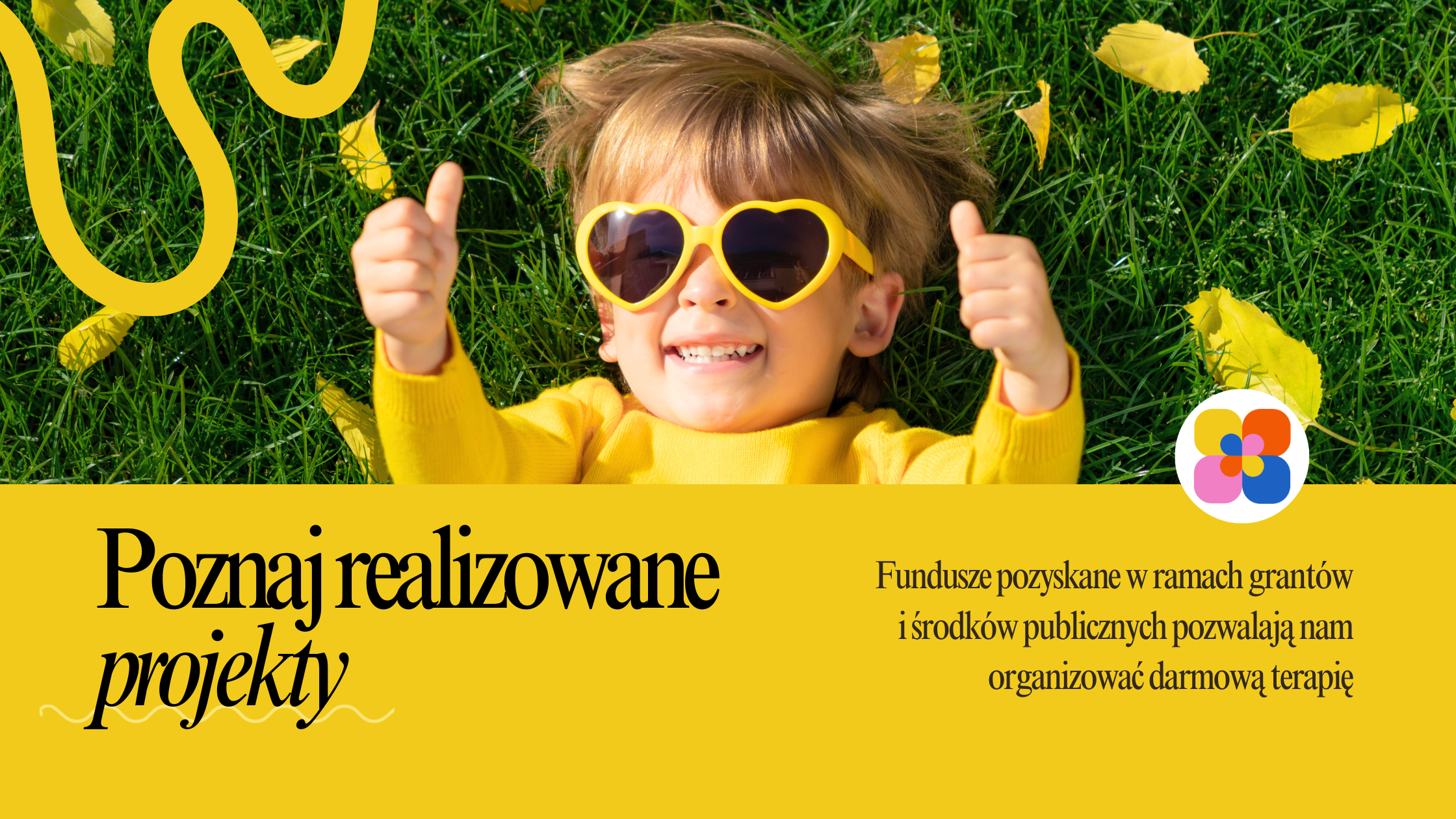banner przedstawiający chłopca w żółtej koszulce w okularach w kształcie serca, który leży na trawie z kciukami uniesionymi w geście OK. Pod spodem na żółtym tle jest napisane "Poznaj realizowane projekty", a obok znajduje się napis, że fundusze pozyskane dzięki grantom i środkom publicznym pozwalają nam organizować darmowe wsparcie